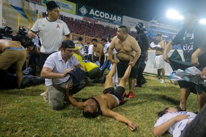 Aficionados al fútbol atienden en la cancha a los heridos por una estampida humana en el estadio Cuscatlán de San Salvador, el sábado 20 de mayo de 2023 