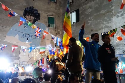 Aficionados de Argentina se reúnen bajo un mural de la difunta leyenda del fútbol argentino Diego Maradona mientras celebran la victoria en el Mundial de Qatar 2022 contra Francia en Nápoles el 18 de diciembre de 2022.