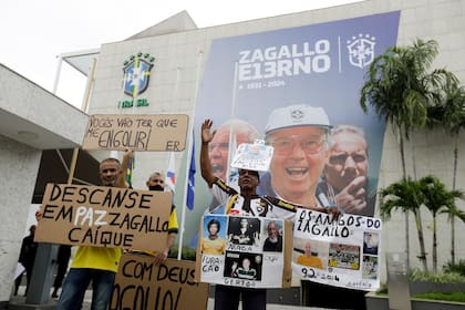 Aficionados del exjugador y seleccionador de Brasil Mario Zagallo sostienen pancartas afuera de las instalaciones de la Confederación de Brasil en donde se realizó el funeral de Zagallo, el domingo 7 de enero