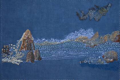 El mar, las rocas y las aves crean un paisaje minimalista y sereno en Sueño despierta, la obra realizada sobre lino, bordada con hilos de rayón y algodón. 