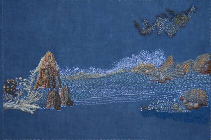 El mar, las rocas y las aves crean un paisaje minimalista y sereno en Sueño despierta, la obra realizada sobre lino, bordada con hilos de rayón y algodón.