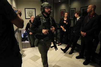 Agentes con equipo táctico suben las escaleras desde el vestíbulo del nivel inferior donde supuestamente fue detenido el tirador después de que se produjeran disparos durante la cena de corresponsales de la Casa Blanca