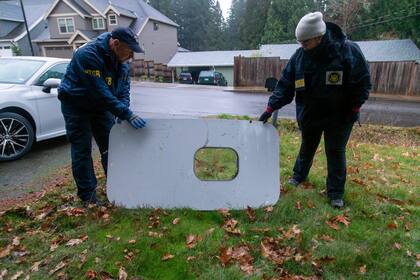 Agentes de la Junta de Seguridad inspeccionando el tapón de la puerta del vuelo 1282 de Alaska Airlines el 8 de enero de 2024 después de ser encontrado en Portland, Oregon. 