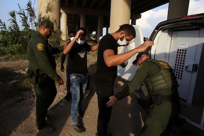 Agentes de la Patrulla Fronteriza de EEUU revisan a migrantes luego de que cruzaron el río Bravo hacia Estados Unidos en Eagle Pass, Texas. el viernes 20 de mayo de 2022. (AP Foto/Darío López-Mills)