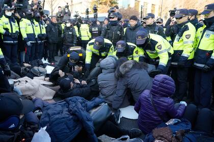 Agentes de la policía arrastran a simpatizantes del presidente destituido surcoreano, Yoon Suk Yeol, cerca de la residencia presidencial en Seúl, Corea del Sur, el jueves 2 de enero de 2025. (AP Foto/Ahn Young-joon)
