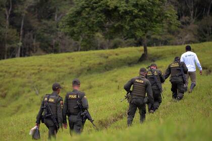 Agentes de la policía colombiana y un rebelde de las FARC patrullan el área donde se produce el acto final de abandono de armas y el fin de las FARC como grupo armado en la Zona de Transición de Normalización Mariana Paez, Buena Vista, municipio de Mesetas, Colombia