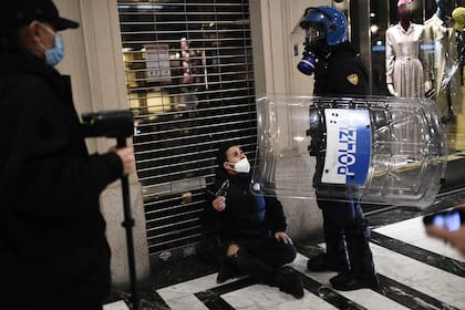 Agentes de la policía italiana detienen a un activista de extrema derecha durante una protesta contra las medidas de restricción del gobierno para frenar la propagación del coronavirus, en el centro de Turín, el 26 de octubre de 2020