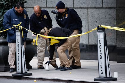 Agentes de la unidad de asesinatos de la policía de Nueva York colocan vasos para marcar los lugares donde cayeron las balas mientras investigan en las inmediaciones del hotel Hilton de Manhattan, donde Brian Thompson, CEO of UnitedHealthcare, fue asesinato a tiros, el 4 de diciembre de 2024, en Nueva York