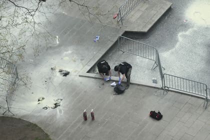 Agentes de policía de Nueva York inspeccionan una mochila dejada en el lugar donde un hombre se prendió fuego en un parque fuera de la corte criminal de Manhattan, el viernes 19 de abril de 2024, en Nueva York. 