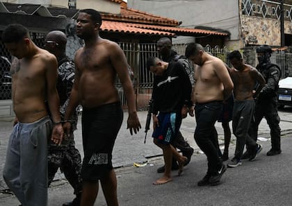 Agentes de policía escoltan a sospechosos arrestados durante la Operación Contención fuera de la favela Vila Cruzeiro, en el complejo Penha, Río de Janeiro