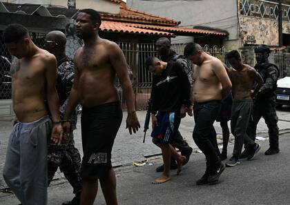 Agentes de policía escoltan arrestados durante la Operación Contención fuera de la favela Vila Cruzeiro, en el complejo Penha, Río de Janeiro, Brasil, el 28 de octubre de 2025