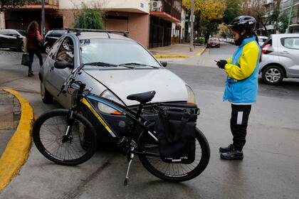 Una agente de la patrulla en bicicleta labra una infracción de un automóvil estacionado en la ochava, obstruyendo una rampa y la ciclovía