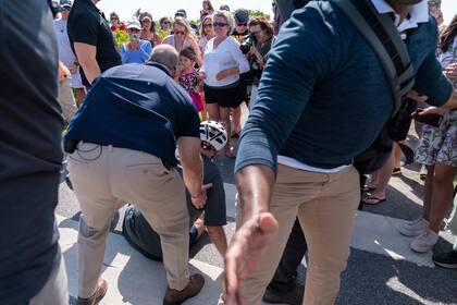 Agentes del Servicio Secreto de Estados Unidos ayudan al presidente Joe Biden a levantarse después de que se cayó al tratar de desmontar su bicicleta para saludar a una multitud en un sendero el sábado 18 de junio de 2022, en la zona de Gordons Pond de Rehoboth Beach, Delaware. (AP Foto/Manuel Balce Ceneta)