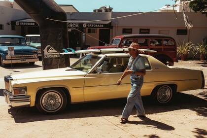 Aguerre, el hombre que logró que el surf sea olímpico, se pasea entre los autos setentosos en los que varios surfistas llegaron al evento