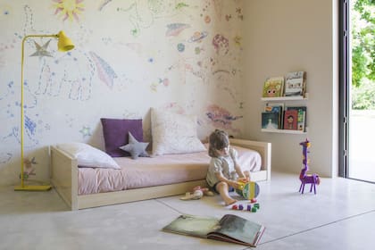Agustina ilustró el empapelado del cuarto de su hija. Cama ‘Oslo Montessori’ (El Corral Muebles), estantes reutilizados, lámpara de pie amarilla (Omniluz). 