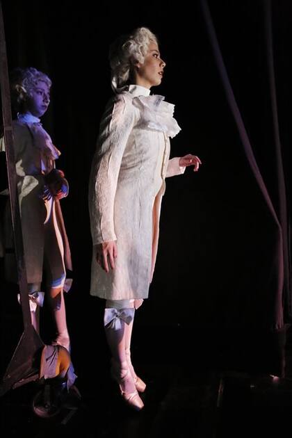 Al borde de la escena: Una joven bailarina caracterizada como cartero espera su hora