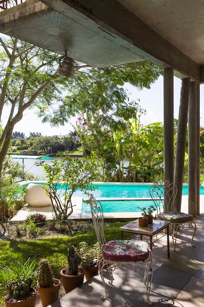 Al borde de la pileta, sillón ‘Pastilla’ de fibra de vidrio (Estudio IK). En primer plano, juego de jardín de hierro heredado.