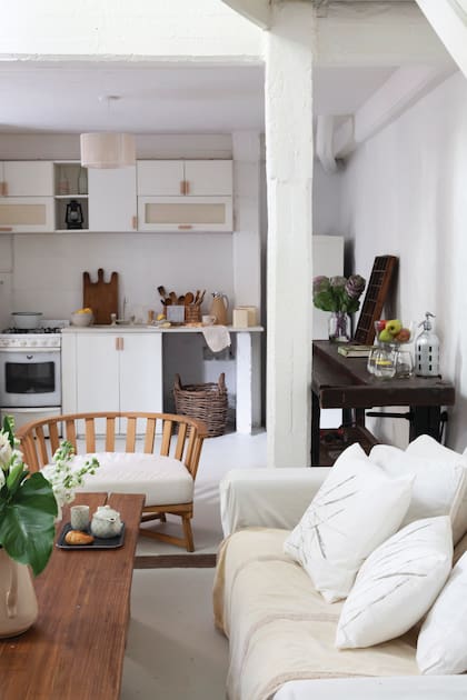 Al costado del sofá, una antigua mesa de trabajo con morsas (The Concrete Bs. As.). Sillón tipo Gervasoni con colchoneta color crudo. Almohadones ‘Espigas’ (Salazar Casa).