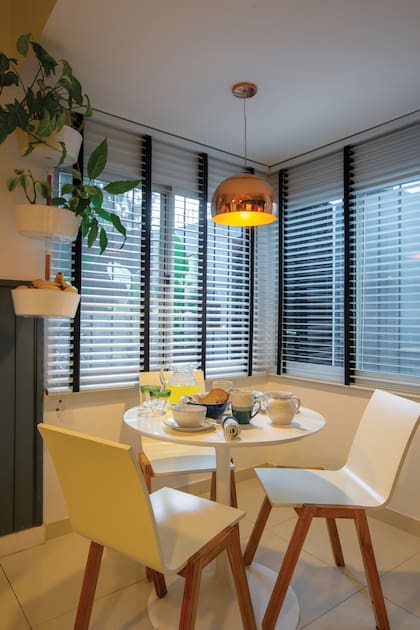 Al desayunador, con muebles contemporáneos, se le sumó un par de cortinas americanas con tiras negras y una jardinera colgante con kokedamas.