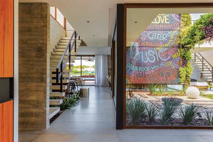 Al entrar, la vista es larga. En el medio aparece un patio interno que hace de fuelle: en la pared, mural de la artista Sol Lua con frases elegidas por los dueños de casa. En la viga –que 'cose' los dos volúmenes–, jardín vertical (Vivero La Magnolia).