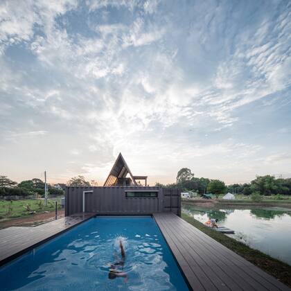Al este, un solo contenedor que alberga un dormitorio adicional da a una piscina rodeada de terrazas que se asoma al embalse cercano.