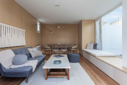 Al fondo, el comedor. Lámpara de pared (Federico Churba). Sillón (Tapicería Carlos Méndez) con manta (Maimará) y almohadones (Lote Propio). Obra textil (Cristina Codern). Puf (Mausy Design).