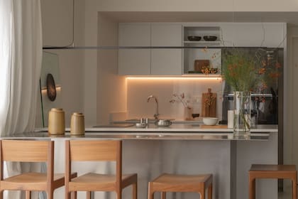 Al frente, sobre la mesada existente en melamina blanca a la que se adosó una barra metálica diseñada por Siuk Studio, artefacto colgante (Huup).