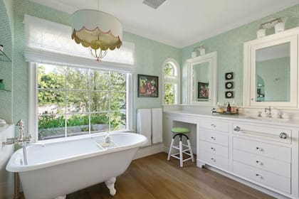Al igual que el resto de los ambientes, el baño refleja el espíritu vintage con su bañadera antigua, la grifería de estilo retro y las paredes revestidas de papel verde agua. 