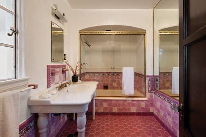 Al igual que el resto de los espacios, los baños respetan el estilo vintage de la casa. El baño principial está ambientado en tonos rosas con detalles en dorado en la zona de la ducha