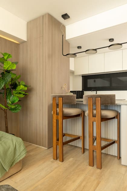 Al ingresar al departamento, se accede a la cocina hacia la derecha. La barra se trabajó con líneas curvas que facilitan la circulación. La base es varillada y laqueada en el mismo tono del mueble de la TV (Estudio Aldo).