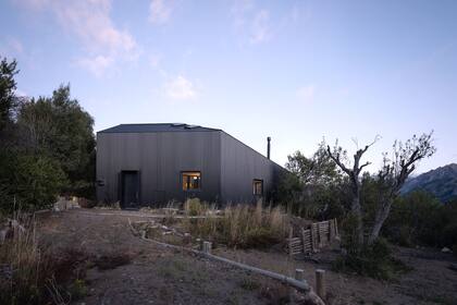 Al llegar, la casa ofrece su cara más cerrada. Una vez dentro, los ambientes principales revelarán las majestuosas vistas hacia el lago y el propio terreno.