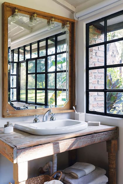 Al otro lado del dormitorio, el vanitory de madera rústica con un espejo, armado por Agostina con listones sobrantes de la obra y lámparas.