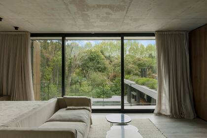 Al pie de la cama, sofá con funda de lino (Landmark), el mismo género elegido para las cortinas.