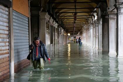 Una mujer camina por la inundación bajo las recovas de la plaza San Marcos.