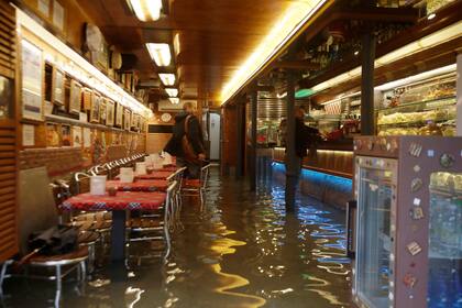 Un hombre compra un café en un bar inundado de Venecia.