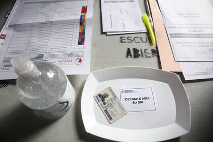 Alcohol en gel y bandeja de plástico para el documento en una de las mesas de la escuela de Juncal 3131