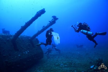 Alejandro Dutto exhibe la bandera argentina en los cañones de cubierta del USS Saratoga