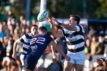 Alejo Novo se dispone a tacklear a Akemeier, que lo prevé y pasa el balón; el fullback salteño, a quien fueron a ver jugar sus padres este sábado, suele ser figura de la Academia.