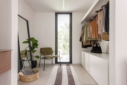 Alfombra (Casa Cruz estudio), poltrona tapizada (Estudio Te). Espejo (Cut Cat) y artefacto de iluminación lineal (Lumishop). Muebles del vestidor diseñados por el estudio en melamina.