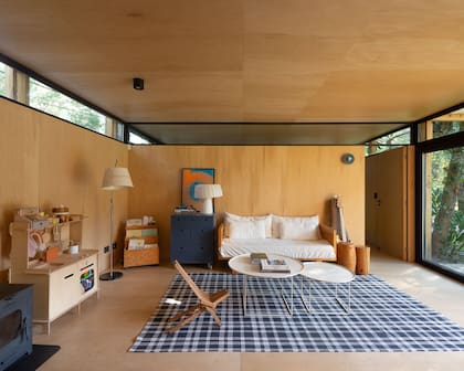 Alfombra del living (Dash & Albert), sillón, mueble azul y mesitas de arrime tipo troncos (carpintería Russo). Lámpara Tolomeo.
