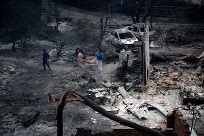 Algunas personas atraviesan el área quemada del predio