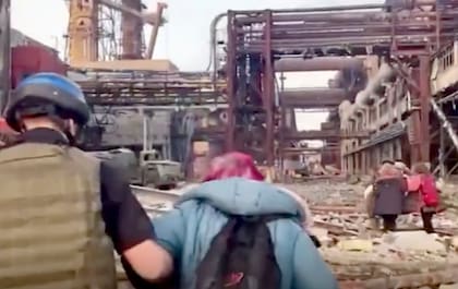 Algunas personas caminan entre los escombros en la planta siderúrgica Azovstal de Mariúpol (Ucrania), en una foto sin fecha suministrada por los militares ucranianos el 1ro de mayo del 2022. (Regimiento de Fuerzas Especiales de Azov de la Guardia Nacional Ucraniana vía AP, File)