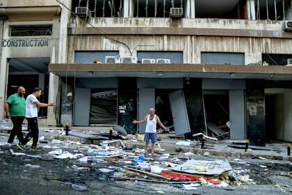 Algunas personas inspeccionan los restos que dejó la explosión en una calle de Beirut