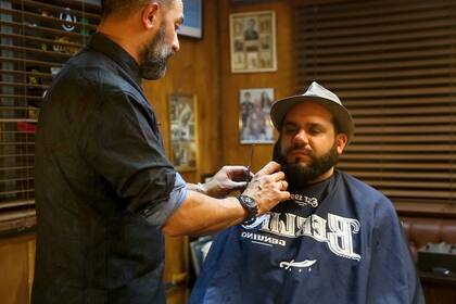 Fernando Elo, de Salón Berlín, le recorta la barba al editor de Brando, Humphrey Inzillo.