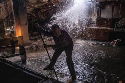Ali Ibrahim Musse ayuda a limpiar el agua de una sede del banco Wells Fargo el sábado 30 de mayo de 2020 en Minneapolis, que fue destruida la noche anterior durante las protestas contra el asesinato de George Floyd