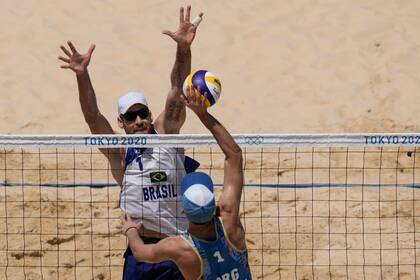 Alison Cerutti, de Brasil, bloquea contra Nicolas Capogrosso, durante un partido de voleibol de playa masculino en los Juegos Olímpicos de Verano de 2020, el sábado 24 de julio de 2021, en Tokio, Japón.