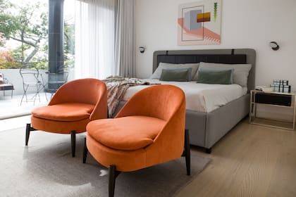 Almohadones, mesas de luz y sillones naranjas (Sol Larrosa). Obra de Valeria Calvo.