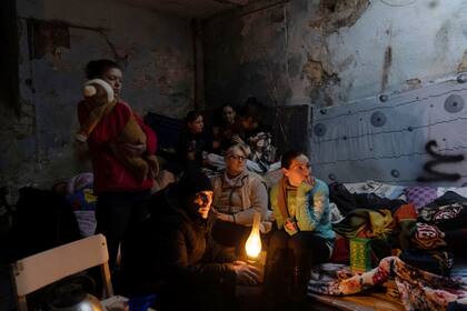 Alumbradas con una lámpare de querosene, varias personas esperan el día en un refugio de Mariúpol (Ucrania), el 6 de marzo del 2022. (AP Photo/Evgeniy Maloletka)