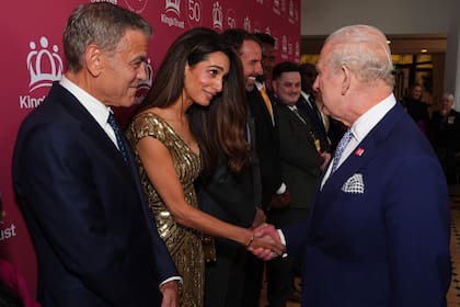 Amal Clooney saluda al rey Carlos III bajo la atenta mirada de George Clooney durante la celebración por el 50° aniversario de The King’s Trust