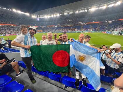 Amistad: argentinos, con una bandera de Bangladesh en el Mundial de Catar 2022.